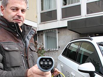 Alfred Gerlach, verantwortlich für den Fuhrpark am Landratsamt, betankt ein neues Hybrid-Dienstfahrzeug mit Strom.  Foto: Benedikt Borst