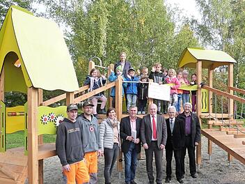 Die Kids mit Kita-Leiterin Sylvia Düreth stehen auf dem neuen Spielgerät, die Offiziellen davor. Im Bild (von links) die Bauhofmitarbeiter Sebastian Hahn und Sven Schmidt, Sandra Schmidt von der Verwaltung, Bürgermeister Siegfried Decker, Bernd Sesselmann und Gunter Heckel vom Lions-Club sowie Pfarrer Stefan Schleicher. Foto: Werner Reißaus