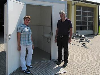Lydia Trütschel, Behindertenbeauftragte der Gemeinde, inspiziert mit Bürgermeister Bernhard Storath das neue mobile behindertengerechte Toilettenhäuschen. Rechts im Hintergrund steht der zum Transport benötigte Anhänger.  Fotos: Monika Schütz