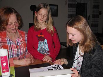 Mutter Karin, Schwester Laura und Konfirmandin Hanna (von links) lassen die Vorbereitung via Begleitmappe Revue passieren.  Foto: Sina Mattheus