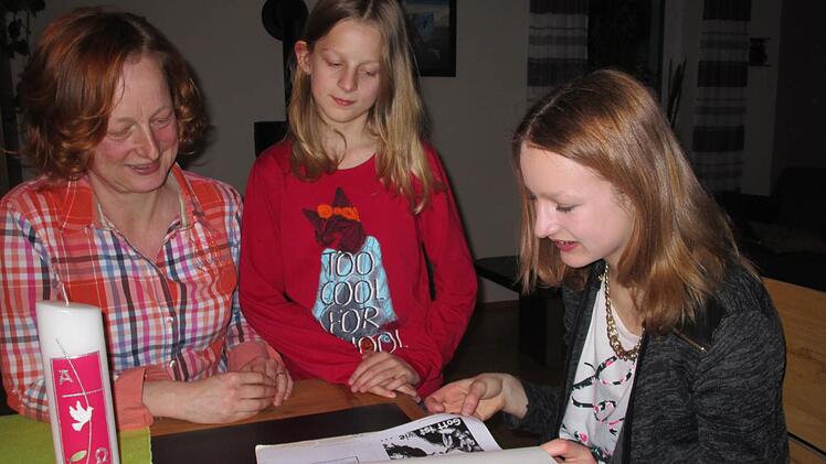Mutter Karin, Schwester Laura und Konfirmandin Hanna (von links) lassen die Vorbereitung via Begleitmappe Revue passieren.  Foto: Sina Mattheus