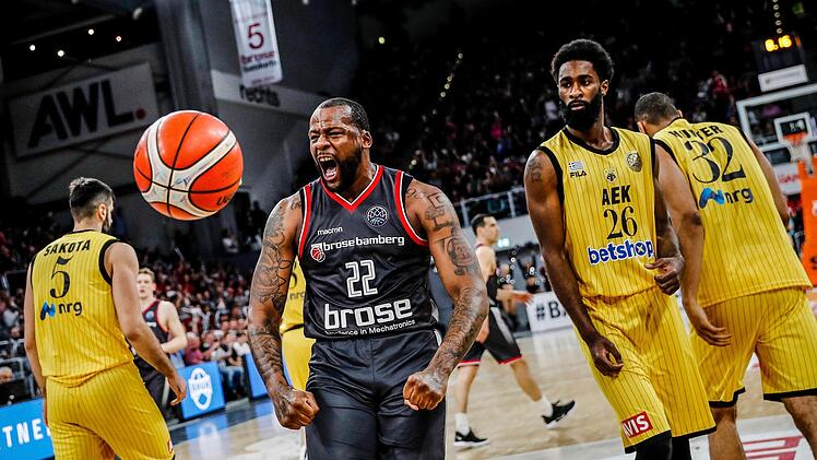 Cliff Alexander nach einem Dunking in Jubelpose. Das Bamberger Kraftpaket war unter den Körben nicht zu stoppen; rechts AEK-Spieler Howard Sant-Roos, der den Bamberger Aufbauspieler Tyrese Rice an die Kette legte. Foto: Daniel Löb