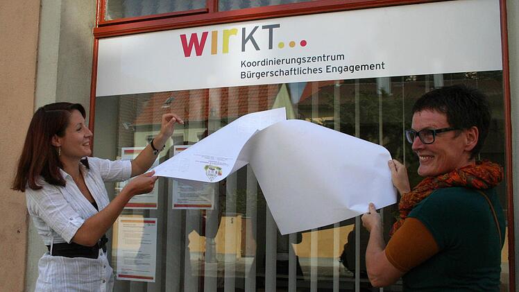 Sandra Thren und die Wettbewerbsgewinnerin Gabi Bergauer aus Astheim enthüllen das neue Logo der Ehrenamtsstelle.  Foto: Paulus