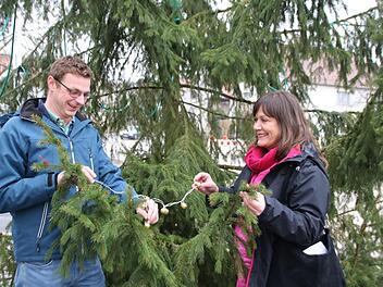 Die Mini-Lichterkette dient als Symbol, mit dem Christoph Müller und Susanne Will, Redaktionsleiterin, den Baum schmücken. Nächstes Jahr sorgt die Saale-Zeitung für den Christbaum in Seubrigshausen. Foto: Thomas Malz