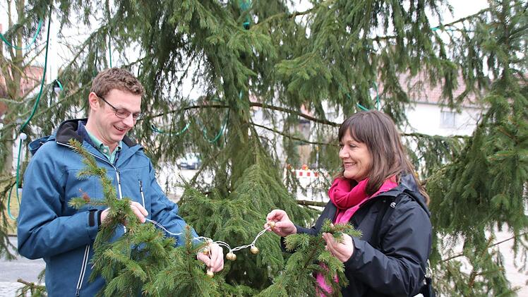 Die Mini-Lichterkette dient als Symbol, mit dem Christoph Müller und Susanne Will, Redaktionsleiterin, den Baum schmücken. Nächstes Jahr sorgt die Saale-Zeitung für den Christbaum in Seubrigshausen. Foto: Thomas Malz