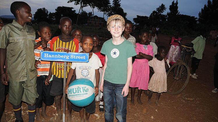 Marc Reif und Kinder aus Busagula stehen am Straßenschild zur Hannberg Street. Foto: Stefan Reinmann