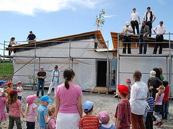 Gespannt lauschen die Vorstandsmitglieder des Waldorfkindergartens, Stefanie Frohmader-Zeller und Michael Hoderlein (hinten links), sowie Kinder und Erzieherinnen dem Richtspruch von Zimmerermeister Günther Stenglein. Foto: Karl Klippel