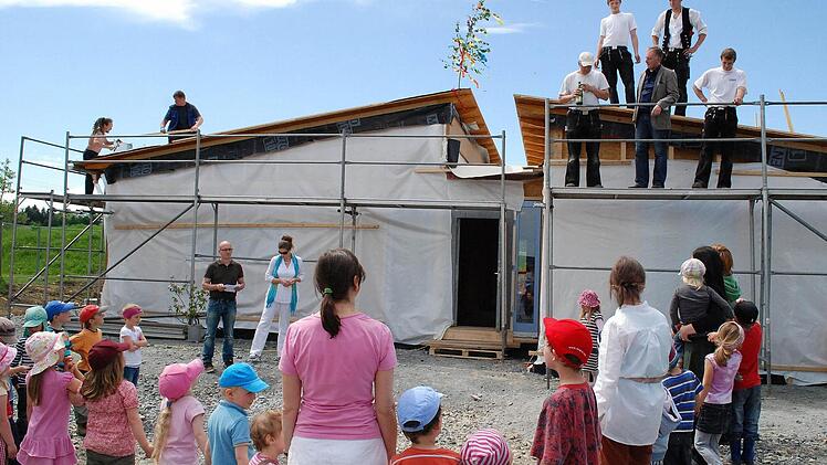 Gespannt lauschen die Vorstandsmitglieder des Waldorfkindergartens, Stefanie Frohmader-Zeller und Michael Hoderlein (hinten links), sowie Kinder und Erzieherinnen dem Richtspruch von Zimmerermeister Günther Stenglein. Foto: Karl Klippel
