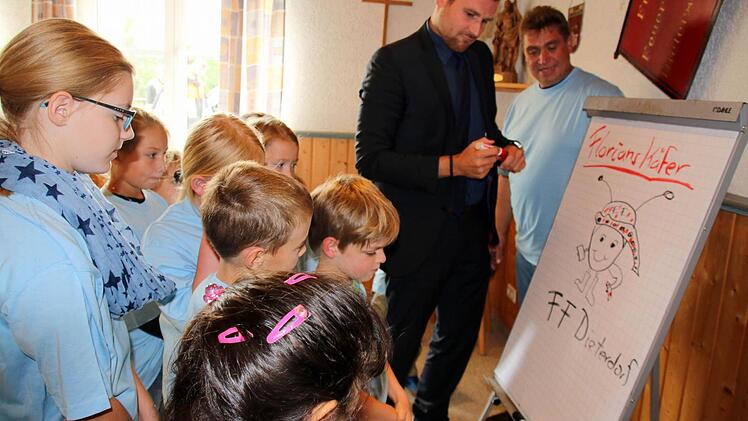 Ob Bürgermeister Martin Mittag das Logo der "Florianskäfer" auch richtig zu Papier bringen kann, beobachteten die Mitglieder der ersten Seßlacher Kinderfeuerwehr und Kommandant Wolfgang Brasch gespannt. Foto: Bettina Knauth