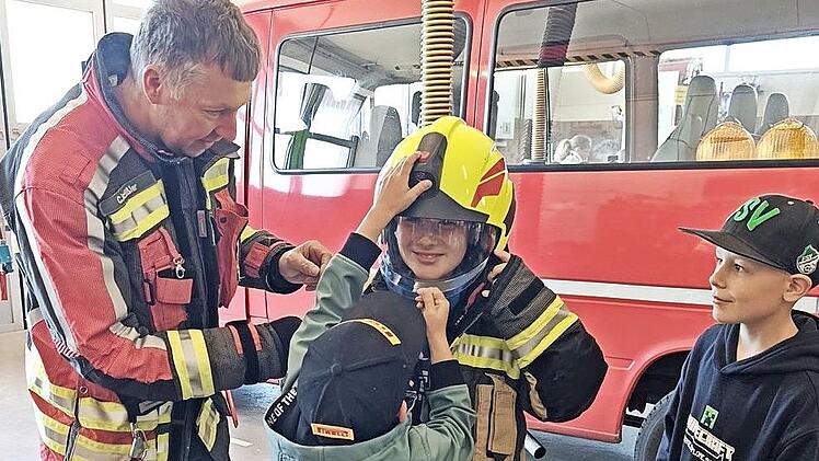 Der Schondraer Feuerwehr-Kommandant Christian Sch&uuml;ssler weist die Schulkinder in die Ausr&uuml;stung der Feuerwehrleute ein.