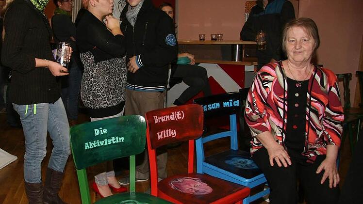 Mit dem Thema Aussitzen in ganz anderem Sinne hat sich die Porträtmalerin Sigrid Groß aus Stammbach beschäftigt: Sie malt Porträts von Williy Brand, Franz-Josef-Strauß oder  aktuellen Persönlichkeiten auf Stühle.