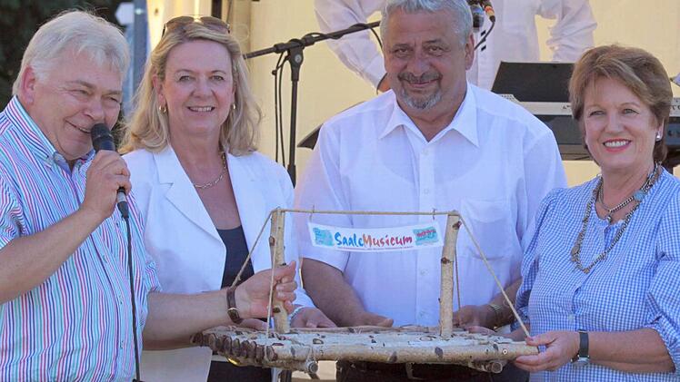 Helmut Lapp (von links) übergibt das hölzerne Floß an Andrea Schallenkammer, Elmar Klug und Bürgermeisterin Brigitte Meyerdirks.