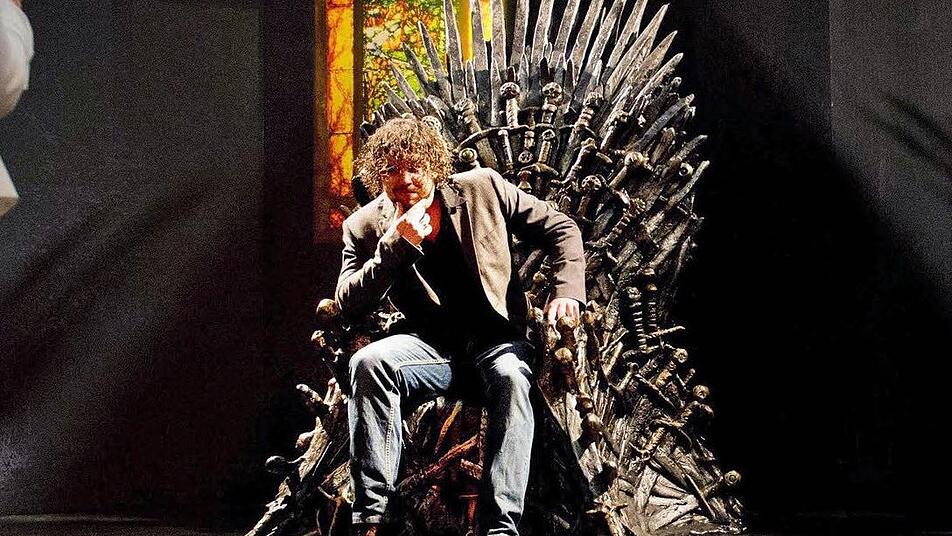 Ein Besucher lässt ein Souvenirfoto von sich auf dem "eisernen Thron" machen. Für ein paar Tage gastiert die Wanderausstellung rund um die beliebte TV-Serie "Game of Thrones" in Amsterdam. Foto: Robin Utrecht, epa