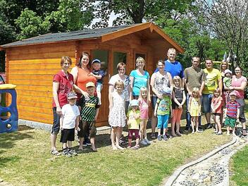 Bei der offiziellen Übergabe der neuen Spielhütte für die Rugendorfer Kindergartenkinder gab es nur zufriedene Gesichter. Das Gebäude, das die Mitglieder des Fördervereins in Eigenleistung erstellt haben, bietet viel Platz, um alle Spielsachen unterbringen zu können. Unser Bild zeigt Vorsitzende Sonja Witzgall (Bildmitte) im Kreis der fleißigen Eltern und Erzieherinnen des Kindergartens Regenbogen in Rugendorf. Foto: Klaus-Peter Wulf