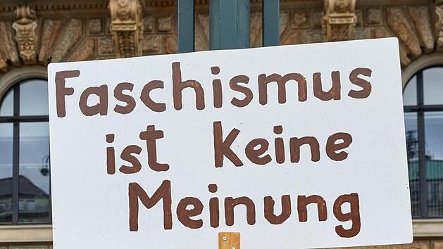Hamburg: Eine Transparent mit der Aufschrift ·Faschismus ist keine Meinung· hängt an einem Laternenmast auf dem Rathausmarkt. Im Hintergrund bilden die Teilnehmer der Demonstration der Organisation «Omas gegen Rechts» unter dem Motto «Keine Macht den Rechten! -Keine AfD in unser Rathaus!» eine Menschenkette am Rathaus. Foto: Georg Wendt/dpa