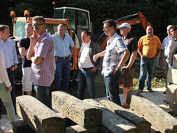 Im Friedhof Unterrodach wird ein kreisrundes Urnengräberfeld geschaffen. Doch zuvor ist eine Stützmauersanierung erforderlich. Die Steine im Vordergrund werden wieder in der Mauer verbaut. Darüber informierte Bürgermeister Norbert Gräbner den Marktgemeinderat bei einer Besichtigungstour.  Foto: Friedwald Schedel
