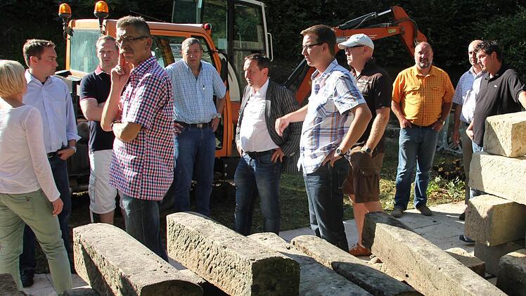 Im Friedhof Unterrodach wird ein kreisrundes Urnengräberfeld geschaffen. Doch zuvor ist eine Stützmauersanierung erforderlich. Die Steine im Vordergrund werden wieder in der Mauer verbaut. Darüber informierte Bürgermeister Norbert Gräbner den Marktgemeinderat bei einer Besichtigungstour.  Foto: Friedwald Schedel