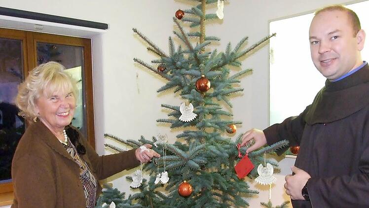 Pater Stanislaus Wentowski und Gitta Biedermann haben den Weihnachtswunschbaum gemeinsam geschmückt. Es ist aber noch ausreichend Platz für viele Wunschkärtchen.