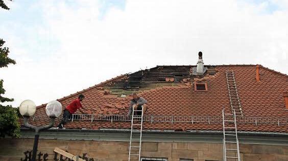 Zwölf Stunden nach dem Brand sind Dachdecker damit beschäftigt, die beschädigten Ziegel abzuräumen.  Foto: Ekkehard Roepert