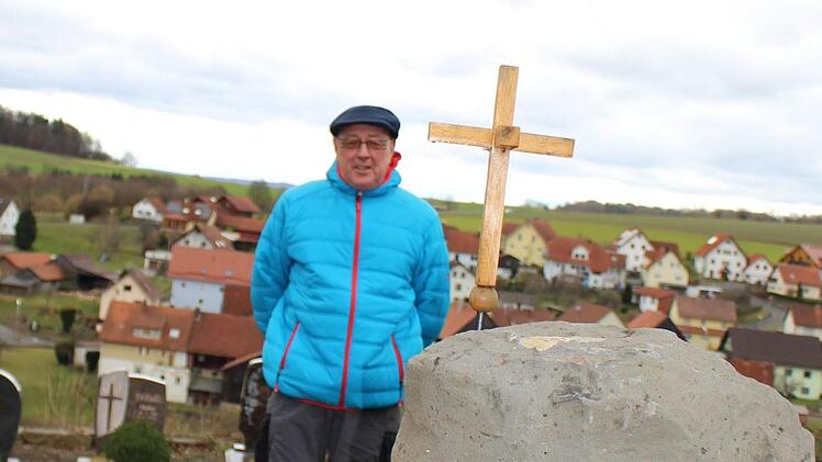 Rolf Kohlhepp zeigt das neu angelegte, anonyme Urnengrab mit Basaltsäule und Kreuz in der Mitte. Foto: Julia Raab