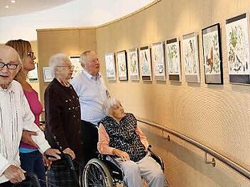 Besucher und Heimbewohner betrachten die farbigen Kalenderblätter aus den 1950er Jahren, die derzeit in der Kleinen Galerie des Seniorenzentrums ausgestellt sind. Foto: Heike Beudert