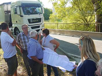Jetzt wird's eng: Während Christian Gunsenheimer, Michael Boßecker, Walter Thamm, Renate Schubart-Eisenhardt, Melanie Dressel und Jürgen Alt (von links) die Unterlagen besprechen, testet ein Lastwagen die Traglast der Rodach-Brücke bei Schloss Wiesen. Foto: Berthold Köhler