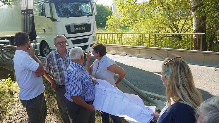 Jetzt wird's eng: Während Christian Gunsenheimer, Michael Boßecker, Walter Thamm, Renate Schubart-Eisenhardt, Melanie Dressel und Jürgen Alt (von links) die Unterlagen besprechen, testet ein Lastwagen die Traglast der Rodach-Brücke bei Schloss Wiesen. Foto: Berthold Köhler
