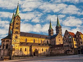 "Earth Hour": Bamberger Dom setzt Zeichen für Klimaschutz Der Bamberger Dom im Sonnenschein mit seinen markanten Türmen vor einem teilweise bewölkten Himmel. Historische Architektur im Vordergrund.