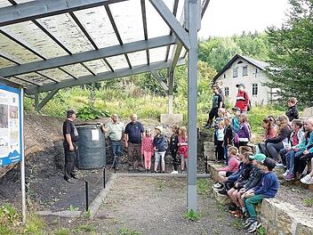 Buben und Mädchen blicken in die Vergangenheit der Bergleute: Unser Bild zeigt das überdachte Stockheimer Geotop mit dem zehn Zentner schweren Teufkübel, im Hintergrund die bergmännische Rentei von 1870 sowie (v. l.) Detlef Heublein, Gerwin Eidloth und Willi Müller.  Foto: Gerd Fleischmann