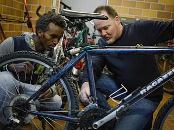 Stefan Frickhofen, Zweiradmechanikermeister bei Radsport Dressel, erklärt Haben (17, links) die Funktionsweise von Kette und Gangschaltung am dunkelblauen Herrenrad. Jeder der 20 jugendlichen Flüchtlinge, die im Spitalgebäude leben, hat ein Rad bekommen.  Fotos: Hendrik Steffens