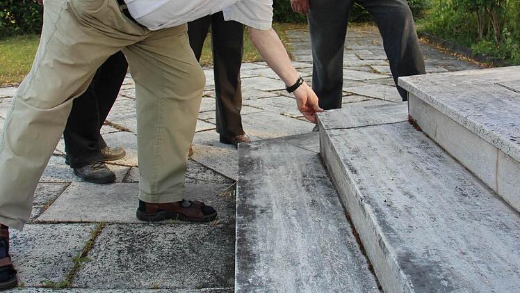 Manfred Fausten begutachtet es mit den Händen. Manche der Travertinplatten vor dem Leichenhaus sind locker.Foto: Eckehard Kiesewetter
