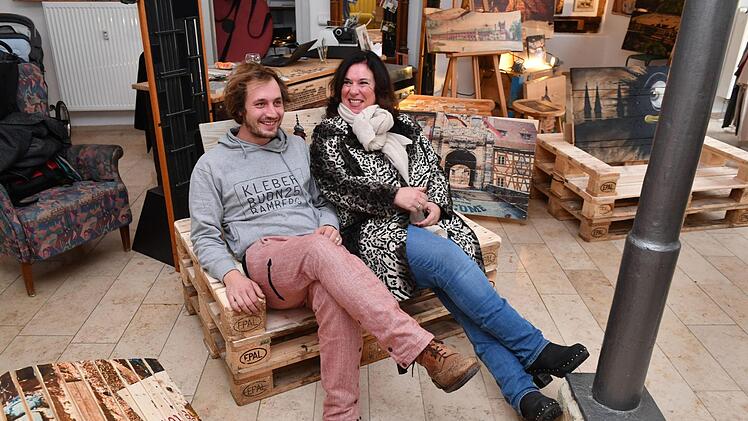 Gisela Schlenker und Christoph Lilge sitzen auf einer Bank aus Europaletten: Die Sitzhöhe ist variabel.