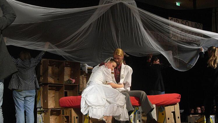 Polly Peachum (Camille Zenses) im Liebeswahn: Sie hat Macheath alias Mackie Messer (Winona Giese) geheiratet und sitzt nun mit ihm auf dem Ehebett.  Foto: Joachim Rübel