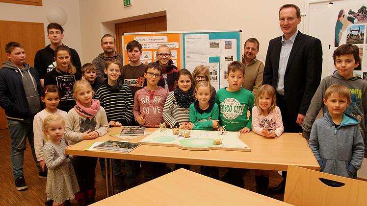 Stolz auf den Abschluss ihrer Planungsarbeit vor Plänen und Modellen die Kinder und Jugendlichen aus Limbach mit 1. Bürgermeister Michael Ziegler (3. von rechts) sowie dem Jugendbeauftragten der Stadtverwaltung Mario Pfister (hintere Reihe 3. von links).