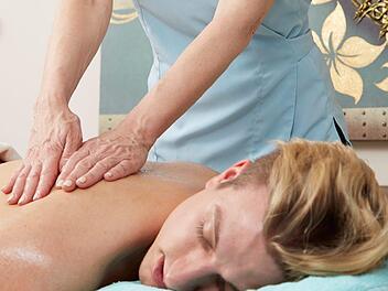 Eine Person genießt eine Rückenmassage in einem Wellness-Hotel. Ruhe und Entspannung stehen im Fokus, ideal nach einem Besuch der Fränkischen Schweiz.
