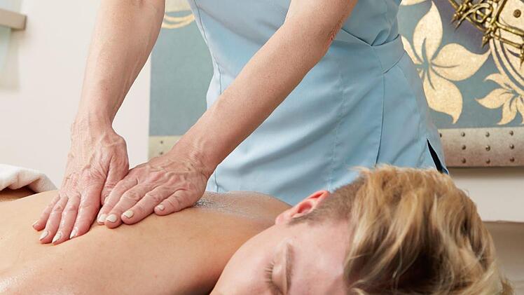Eine Person genießt eine Rückenmassage in einem Wellness-Hotel. Ruhe und Entspannung stehen im Fokus, ideal nach einem Besuch der Fränkischen Schweiz.
