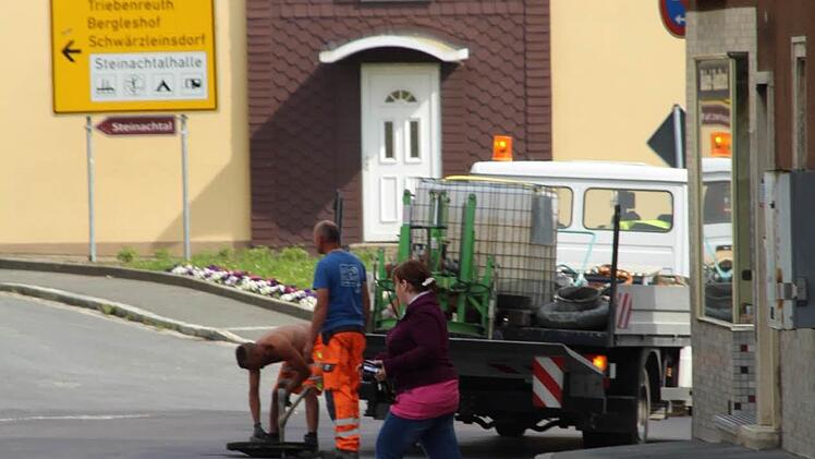 Die Restarbeiten nach der Fahrbahnerneuerung auf der Bundesstraße 303 in Stadtsteinach laufen. Hier befreien Arbeiter die Kanaldeckel von Asphaltrückständen. Foto: Matthias Beetz