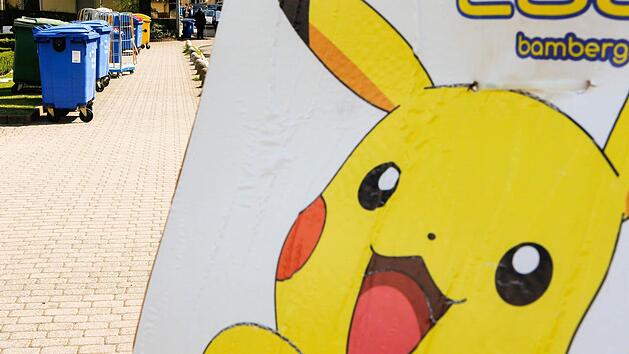 Ein gelbes Pok&eacute;mon-Plakat vor der Tourist-Info in der Geyersw&ouml;rthstra&szlig;e. Im Hintergrund steht der M&uuml;ll zu Abholung bereit.  Foto: Matthias Hoch