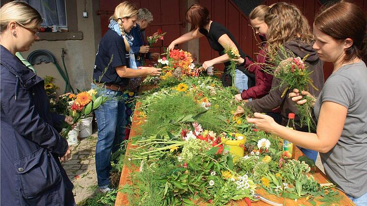 Viele fleißige Hände sortieren, schneiden und binden die gespendeten Blumen.