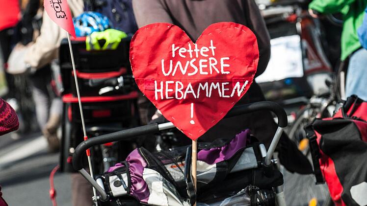 Ein Transparent in Herzform ist am 12.04.2014 in Berlin bei einem Protestumzug für den Erhalt der freien Geburtenhilfe an einem Radanhänger festgemacht. Nach Angaben der Polizei nahmen schätzungsweise 2000 Menschen an einer Demonstration gegen die geplante Erhöhung der Versicherungsprämien für freiberufliche Hebammen teil. Foto: Paul Zinken/dpa