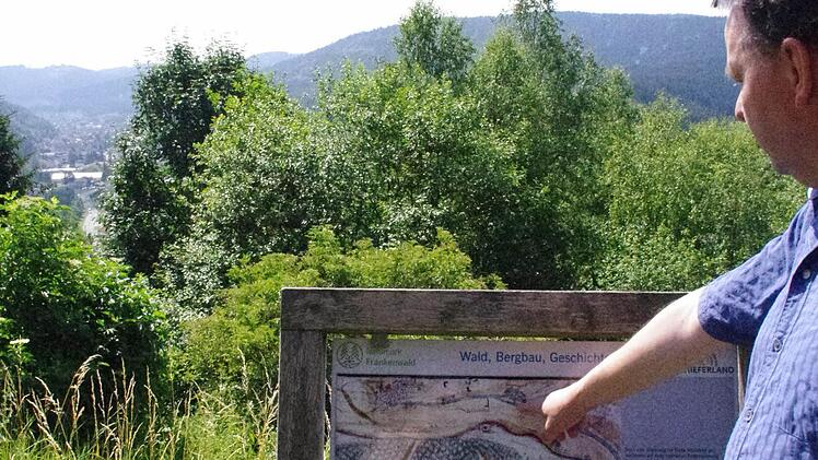 Harald Tragelehn zeigt eine historische Karte von Wallenfels auf einer Hinweistafel. An dieser Stelle des Geopfads eröffnet sich auch ein Ausblick auf die Flößerstadt. Foto: Marco Meißner