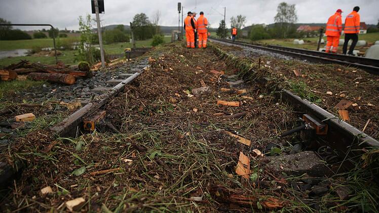 Bahnarbeiter arbeiten am 30.05.2016 in den Nähe von Lehrberg bei Ansbach (Bayern) an einer nach einer Überschwemmung nach einem Unwetter durch Erde und Baumreste blockierten Bahnstrecke. In der Nacht wurden zahlreiche Straßen und Keller überflutet und Erdrutsche blockierten Straßen. Foto: Daniel Karmann/dpa