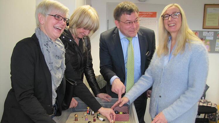 Mithilfe des Sandkastens un der dazugehörigen Spielzeugfiguren werden Beziehungssituationen in Problemfamilien anschaulich dargestellt (von links). die Stadträtinnen Gabriele Morper-Marr und Monika Ufken, Stadtrat Christian Müller und Antje Schäfer, die neue Leiterin der Erziehungs- und Familienberatung. Foto: Martin Koch