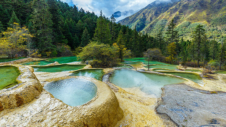 Huanglong Nationalpark Sichuan China Naturwunder UNESCO Weltnaturerbe Kalksinterterrassen Pools Naturlandschaft Reiseziele Jiuzhaigou Tourismusbranche L&auml;ndliche Gebiete Naturschutzgebiet Berglandschaft Touristen Ausl&auml;ndische Besucher Hochsaison Infrastruktur Sanit&auml;re Anlagen Barrierefreiheit Servicequalit&auml;t Regulierung Volksrepublik Reiseindustrie Wirtschaftswachstum Zweitst&auml;dte Urlaubsziel Wandern Naturerlebnis