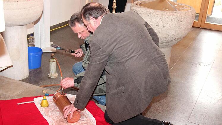 Nun wird die Kapsel vom Spengler Georg Ströbel (hinten) unter Mithilfe von Architekt Helmut Popp zugelötet.