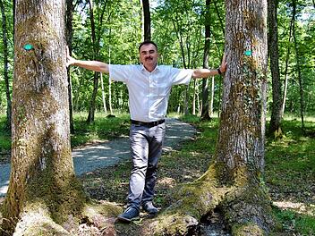 Nüdlingens Bürgermeister Harald Hofmann steht zwischen zwei Friedhofsbäumen, die zum Nüdlinger Naturfriedhof gehören.  Foto: Sigismund von Dobschütz