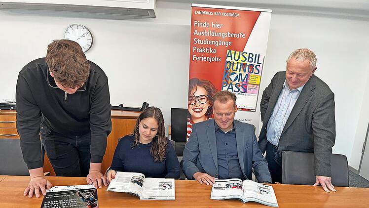 Die Auszubildenden (von links) Nikolas Tiefenbach und Zoe Grom aus dem ersten Lehrjahr sichten gemeinsam mit Frank Bernhard (Wirtschaftsf&ouml;rderung im Landratsamt Bad Kissingen) und Landrat Thomas Bold den neuen Ausbildungskompass.