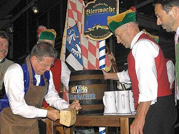 Landrat Klaus Peter Söllner (links), der Finanz-Vorstand der Kulmbacher Brauerei, Otto Zejmon (rechts), und Mitglieder des Büttnervereins schauten genau hin, aber es ging kein Tropfen daneben: Henry Schramm meisterte den Probeanstich am Montag mit Bravour. Foto: Peter Müller
