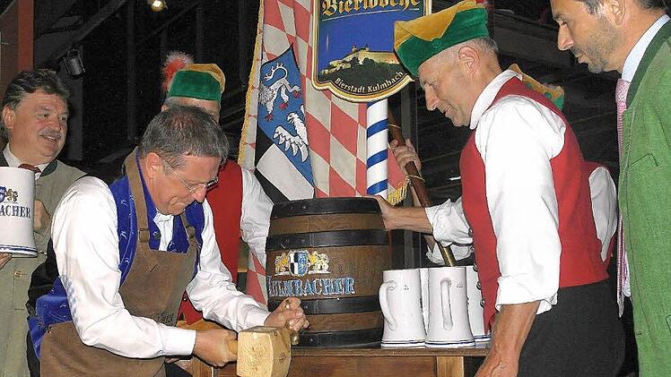 Landrat Klaus Peter Söllner (links), der Finanz-Vorstand der Kulmbacher Brauerei, Otto Zejmon (rechts), und Mitglieder des Büttnervereins schauten genau hin, aber es ging kein Tropfen daneben: Henry Schramm meisterte den Probeanstich am Montag mit Bravour. Foto: Peter Müller