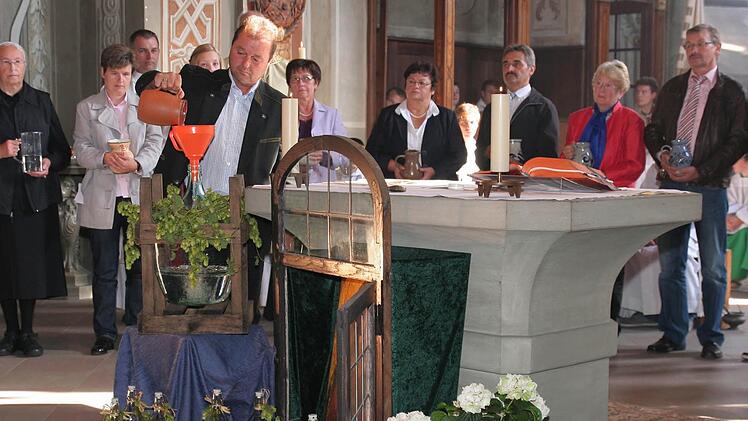 Die Vertreter der drei Pfarrgemeinden sind mit ihren Wasserkrügen um den Altar aufgestellt.  Wolfgang Lurati  schüttet sein Gefäß  während des symbolischen Aktes zur Errichtung der Pfarreiengemeinschaft in den großen Wasserballon.  Fotos: db